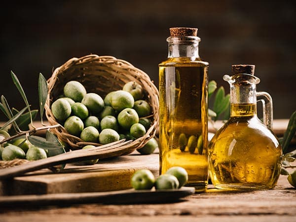 Olive oil with fresh olives on rustic wood